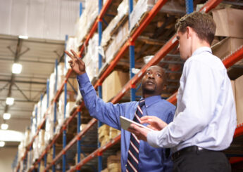 Two Businessmen With Digital Tablet In Warehouse Talking